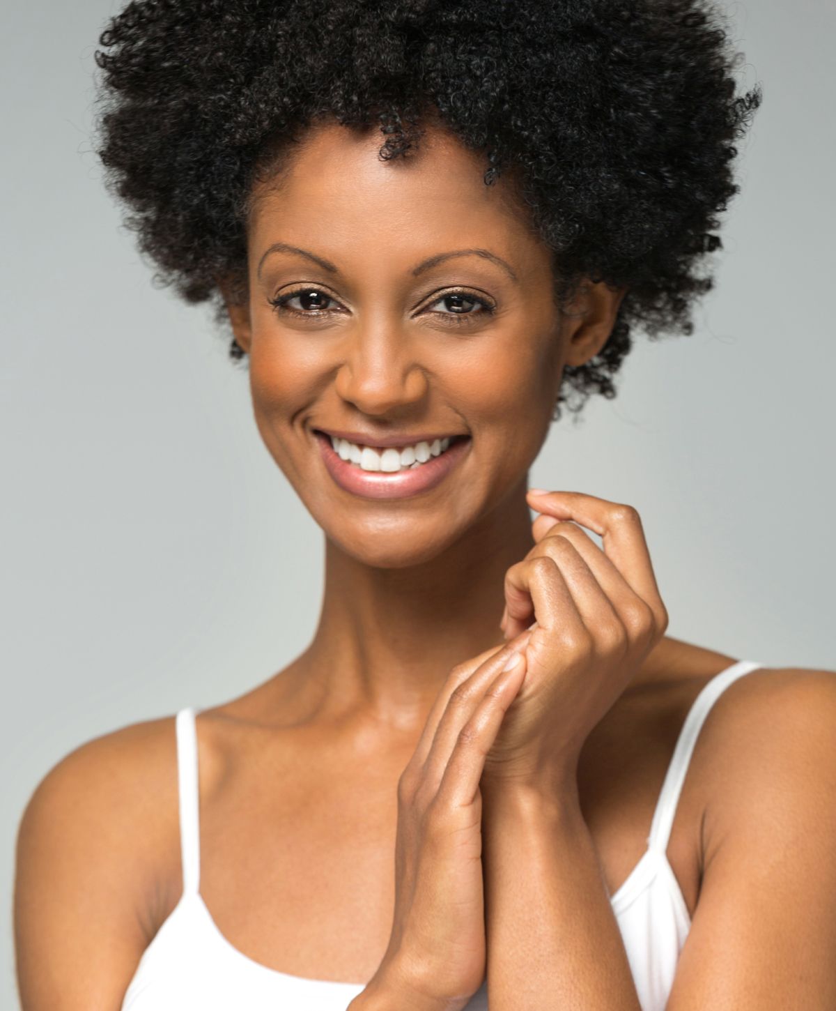 Smiling laser skin rejuvenation patient model with natural curls and soft skin.