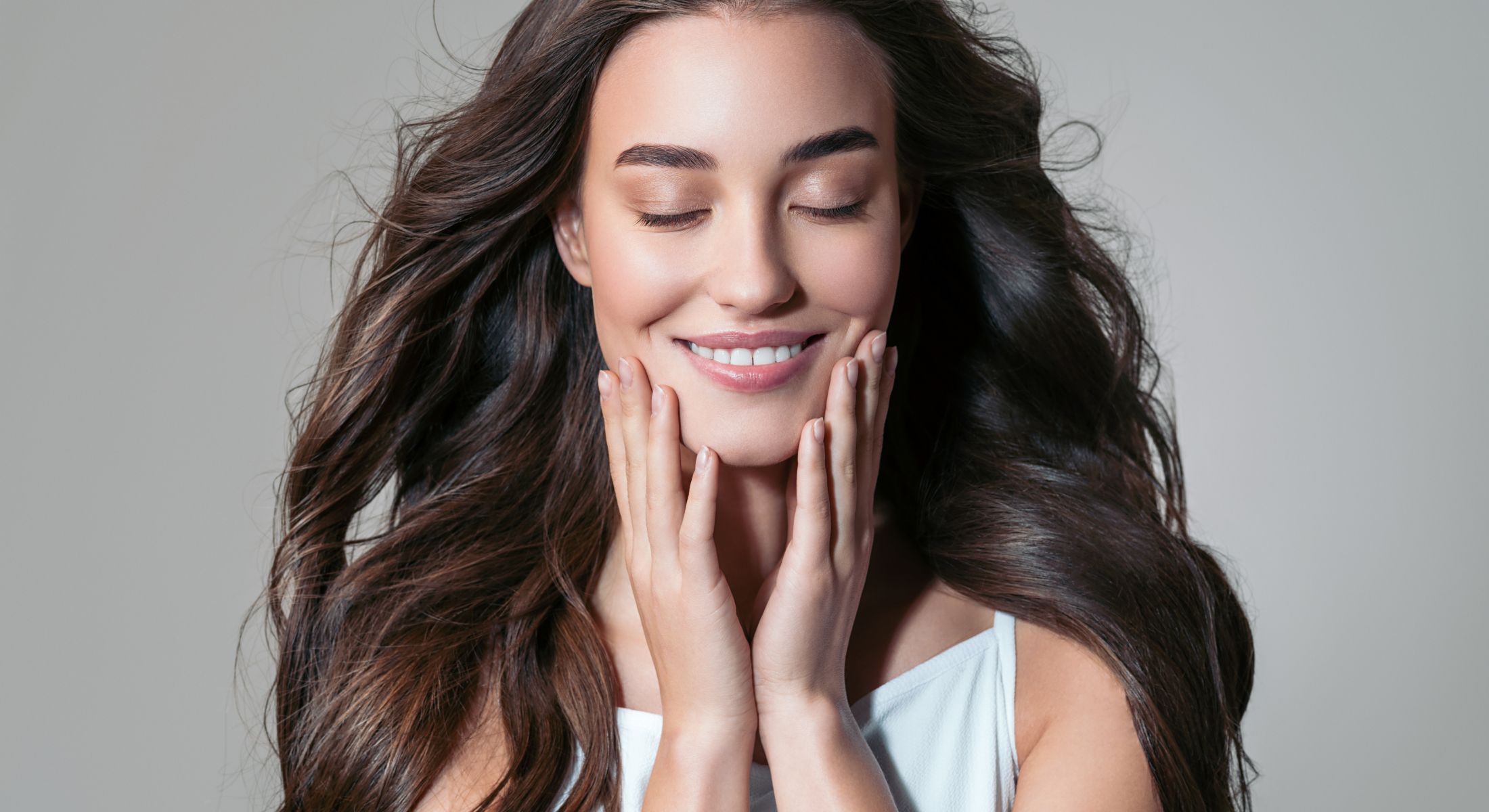 laser hair removal patient model smiling while touching her face with both hands