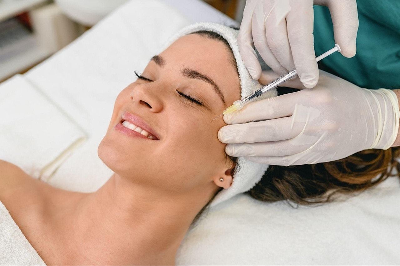 Woman receiving cosmetic facial treatment in spa.